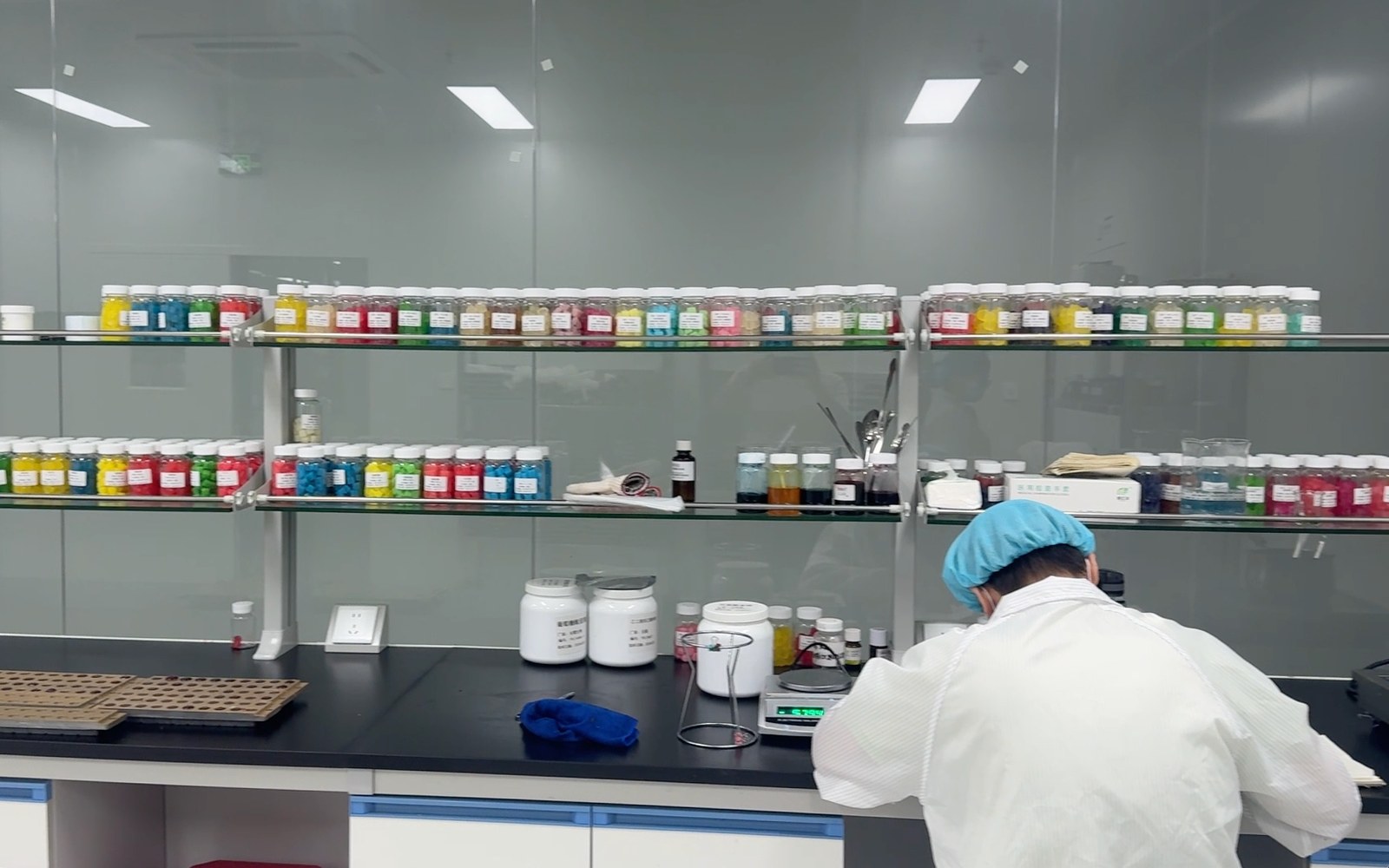 NuCoreBio formulation team member working at a lab bench with colorful raw ingredient jars behind